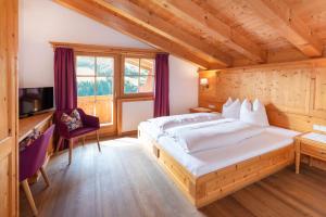 阿尔卑巴赫落叶松旅馆的一间带大床和电视的卧室