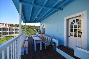 小琉球岛薇多莉亚乡村花园民宿的阳台设有长椅和蓝色墙壁上的桌子