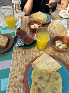 马拉喀什Riad Le Petit Joyau的餐桌,带食物盘和橙汁杯
