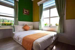 小琉球岛薇多莉亚乡村花园民宿的一间拥有绿色墙壁的卧室和一张窗户床