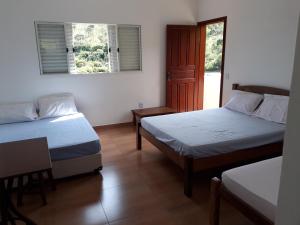 卡舒埃拉坎普Sítio da Serra em Ouro Preto MG的客房设有两张床和一扇窗户的门