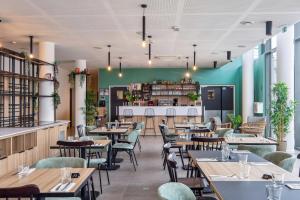 科隆布All Suites Paris Ouest Colombes的餐厅设有木桌和椅子,拥有绿色的墙壁