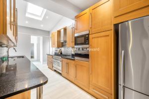 芬奇利Extra Large, Modern Family Home in Finchley London Close to Station and Central London的厨房配有木制橱柜和不锈钢冰箱。