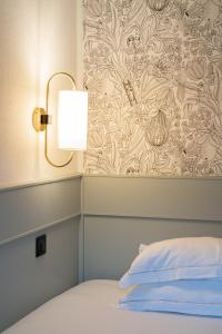 巴黎德福乐西酒店的一间卧室配有一张带灯和壁纸的床