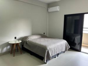 锡诺普Studios Mobiliados - Ambar Ipanema的一间卧室配有一张床和一张小桌子