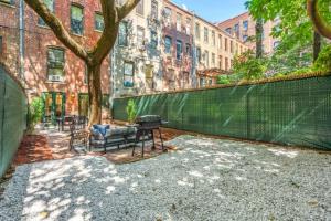 纽约Newly Renovated 2BR w Rare Private Backyard and BBQ的一个带树、长凳和围栏的庭院