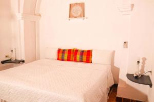 AhuachapánLa Casa de Mamapán Hotel Colonial Ahuachapan的白色卧室配有一张带色彩缤纷枕头的床
