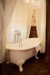 圣马洛科伦姆比城堡酒店的浴室设有白色浴缸,配有窗帘