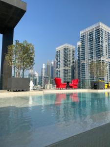迪拜Modern 2BR and maid room with big terrace city walk的城市前的游泳池,带红色椅子