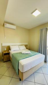 邦比尼亚斯Residencial 364 - Localização privilegiada à 5min da praia的一间卧室配有一张带绿毯的床和窗户。