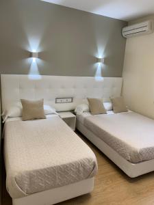 哈拉马河畔帕拉库埃略斯埃尔罗西奥旅馆的一间设有两张床的房间和墙上的两盏灯