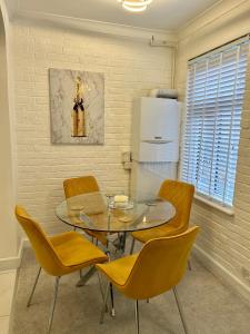 伦敦New! Supreme Apartment - Near Tube Stations的一间设有玻璃桌和黄色椅子的用餐室