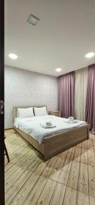 第比利斯7客房酒店的一间卧室配有一张大床、木地板和紫色窗帘
