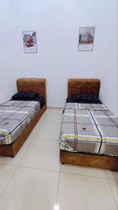 淡马鲁Humairah Homestay - Near Bandar Temerloh的两张睡床彼此相邻,位于一个房间里