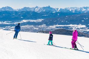 博登斯多夫Feriennest Ossiachersee的三人在雪覆盖的滑雪场滑雪