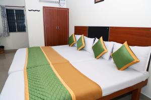 钦奈Royal Green - Airport Stay的一间卧室配有一张带色彩缤纷枕头的大床
