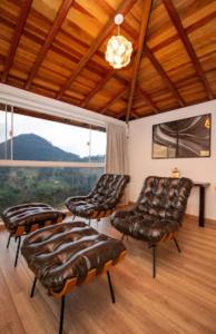贡萨尔维斯Pousada Colina das Andorinhas的一间设有皮椅和大窗户的客房