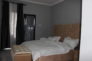 MunyonyoMHP Apartments的一间卧室配有一张大床、一个软木床头板和一扇窗户。