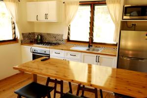 Mt Warning Rainforest Park的厨房配有木桌和不锈钢冰箱。