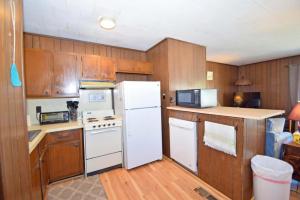 大洋城第79街103号度假屋的厨房配有白色冰箱和木制橱柜。