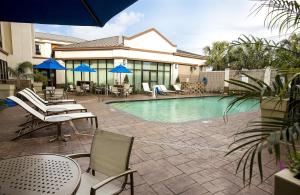 Saint Rose新奥尔良机场智选假日酒店及套房的一个带桌椅和蓝伞的游泳池