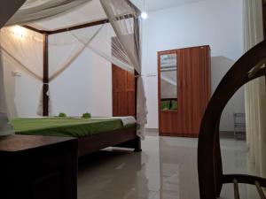 马特勒Muthuarana Villa Matara的一间卧室配有天蓬床和镜子