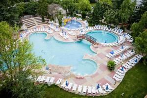 阿尔贝纳Hotel Laguna Garden的享有带椅子和遮阳伞的大型游泳池的上方景色。
