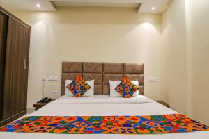 齐拉克普尔FabHotel Prism Grand的一间卧室配有一张带彩色毯子的床