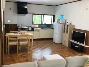 安昙野市陽なた山荘的厨房配有沙发、桌子和冰箱。