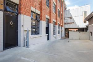 弗里曼特Jarrah Loftprime Location Freo Warehouse的砖楼前的一个空停车位