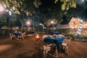 DhanwārSaalwood Safari Lodge的一间晚上配有蓝色桌椅的餐厅