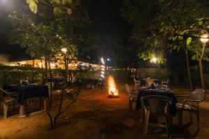 DhanwārSaalwood Safari Lodge的一间晚上带桌子和火的餐厅