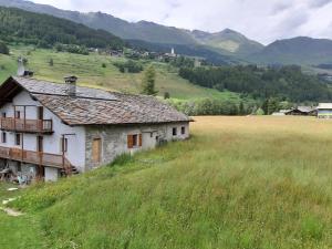 尚波吕克The Snow - Appartamento Panoramico con Balcone的田野上山丘上的一座老房子