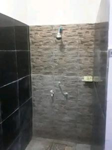 吉利特拉旺安Creative Homestay的带淋浴的浴室(带石墙)