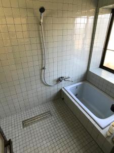 阿苏市Gentou - Vacation STAY 28719v的白色瓷砖浴室设有浴缸和窗户。