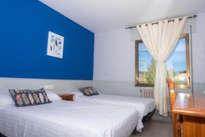索里亚Hostal Venta de Valcorba的配有两张床铺的蓝色墙壁和窗户