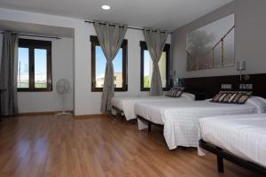 索里亚Hostal Venta de Valcorba的客房设有四张床、窗户和木地板。