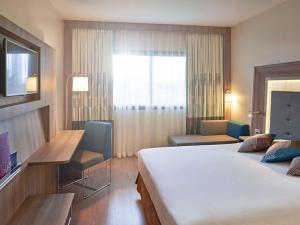 大坎普大坎普诺富特坎酒店的酒店客房设有一张大床和一张书桌。