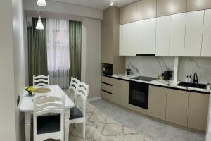 比什凯克Rent Apartment的厨房配有白色橱柜和桌椅