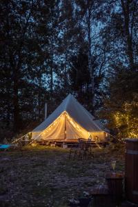 Glamping in - luxury tent的大型帐篷,晚上在田野里摆放椅子