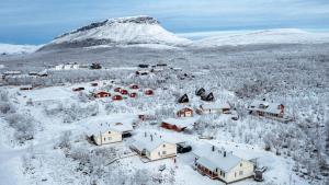 基尔匹斯扎我维Aurora Apartment Kilpisjärvi的被雪覆盖的村庄,背景是山
