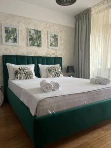 雅西Neolife Copou Apartment的卧室内的一张带毛巾的绿色床