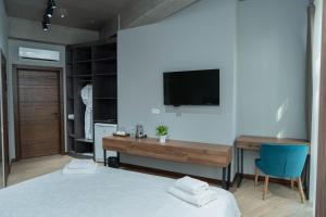 比什凯克Gastello hotel的一间卧室配有一张床、一张书桌和一台电视。
