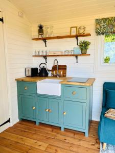巴特尔The Green Hut的厨房配有蓝色橱柜和水槽