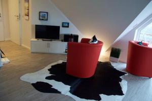 万根沃格Bootshaus SunDeck - Strandnah in den Dünen的客厅配有2把红色椅子和电视