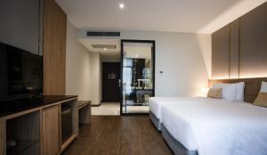 曼谷SAM E Hotel Bangkok Sathorn的酒店客房,配有床和电视