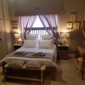 布隆方丹Rubyred Cottage的卧室配有带枕头的大床和窗户。