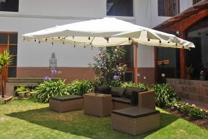 库斯科圣佩德罗修道院酒店的庭院配有白色遮阳伞、沙发和椅子