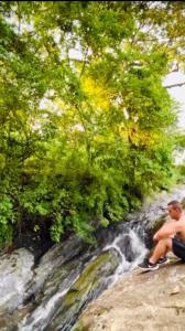 阿瓜斯迪林多亚Aconchego no Domo com Ofurô 7,5km centro Águas de Lindoia com CORTESIA的坐在瀑布旁长凳上的人