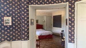 莱斯卡珀利斯博尔波Chambres d'Hôtes Manoir de Beaumarchais的一间卧室配有床和壁纸覆盖的墙壁